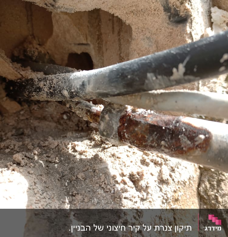 צינורות מתכת חלודים בקיר עם טיח מתפורר